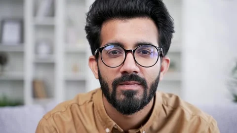 Close up portrait of young handsome bearded man in shirt sitting in living room  Stock Footage 252206333