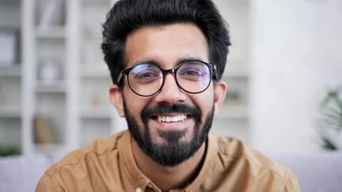 Close up portrait of young handsome bearded man in shirt sitting in living room  Stock Footage 252206335