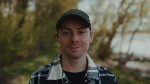 Close up portrait of a young man in a baseball cap looking at camera in nature Stock Footage 333102988