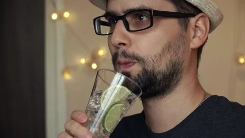 Close-up portrait of a young man drinking mineral water with lime Stock Footage 98750316