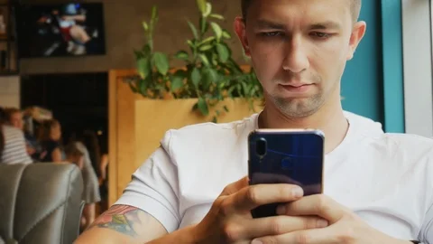 Close-up portrait of young man uses mobile phone in cafe Stock Footage 110734769