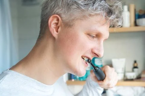 Close up portrait of Young Man is using electric ultrasound toothbrush. Male Stock Photos
