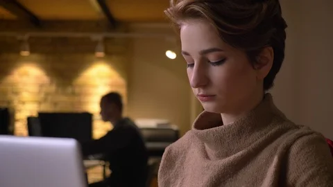 Close-up portrait of young short-haired woman attentively working with laptop in Stock Footage 100932059