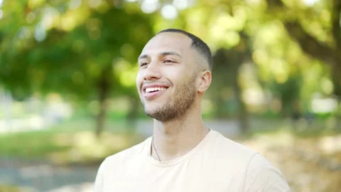 Close up portrait of a young smiling man in a t-shirt standing and relaxing with Stock Footage 234876693
