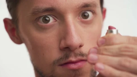 Close up portrait of young stupid guy with brown eyes play with pink lipstick Stock Footage 147557175