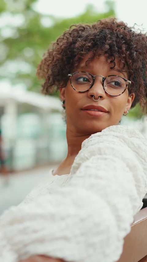 Close-up portrait of young woman in glasses sits on a bench smiling and looking Stock Footage 227004853