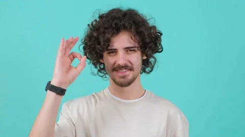 Close up of a positive curly haired young man showing ok gesture with fingers. Stock Footage 151352735
