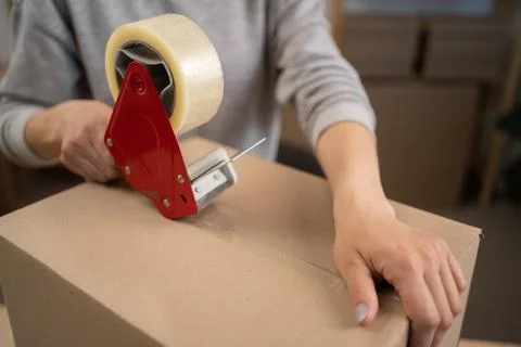 Close up of post office worker taping cardboard box. Postal service employee  Stock Photos