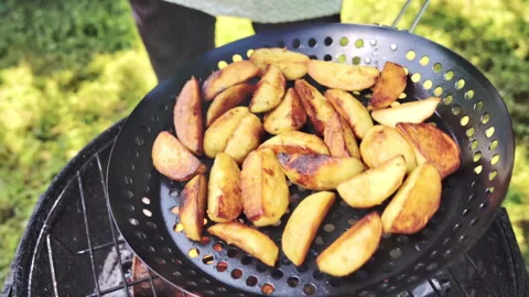 Close-up of potatoes cut into slices being grilled on charcoal Pan. Stock Footage 317932931