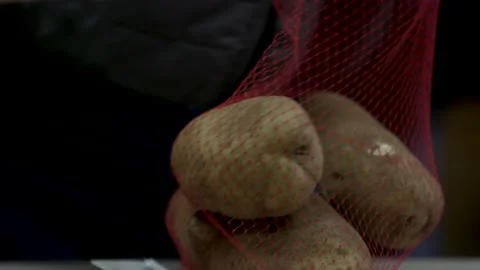 Close-up of a potatoes getting put in a sack at a food bank donation for charity Video stock 130994503