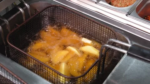 Close-up of potatoes in large slices is cooked in a deep fryer. Stock Footage 267286105