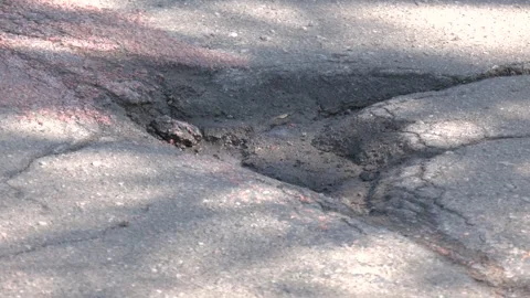 Close-up of a pothole on worn asphalt road surface 스톡 동영상 316516253