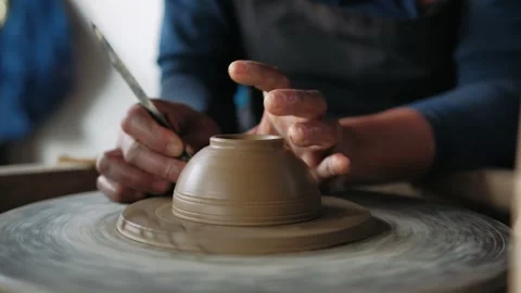 Close up of potter hands creating clay bowl on a spinning pottery wheel in a Stock Footage 325211976