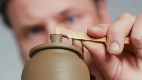 Close-up.potter removing excess clay from the handle of the lid of a clay teapot Stock Footage 145543846