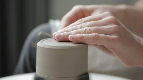 Close-up of potter's hand makes a groove on the bottom of a clay mug. Stock Footage 90132180