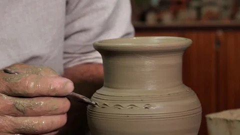 Close-up of a potter's hand making a pattern on a clay jar on a potter's wheel. Stock Footage 246618288