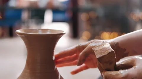 Close-up of potter's hands covered with clay making beautiful vase on throwing Stock Footage 229265239