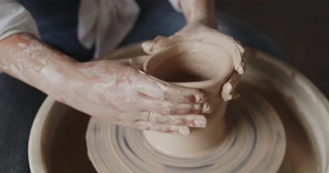Close-up of potter's hands working with clay on poterry wheel in workshop Stock Footage 143078023