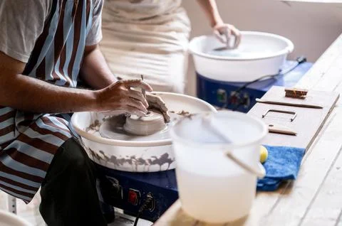 Close up of pottery artist using tool to a make hole on clay on throwing wh.. Stock Photos