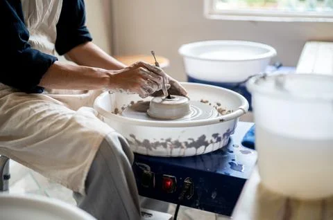 Close up of pottery artist using tool making a hole on clay on throwing whe.. Stock Photos