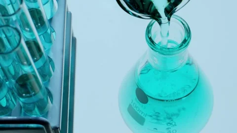 Close Up of Pouring Blue Chemical Solution into Erlenmeyer Flask in Lab Stock Footage 337320677