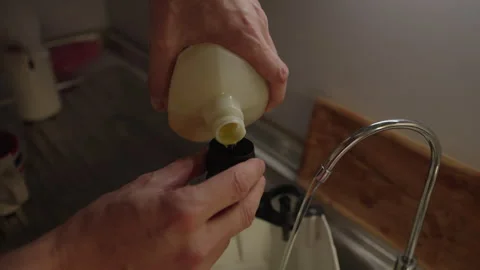 Close-up of pouring cleaning detergent from bottle into reservoir cap of washing Stock Footage 312377143
