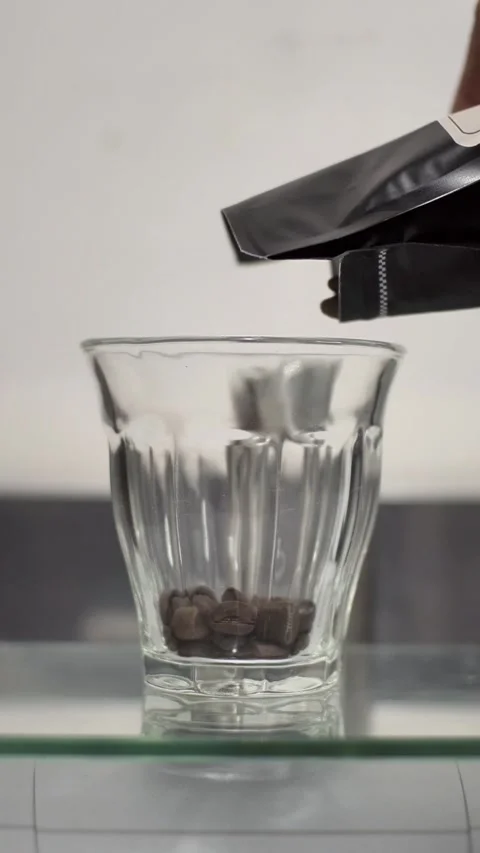 Close Up Pouring Coffee Beans from Packaging into Glass Cup Vertical Format 库存影片 331059339