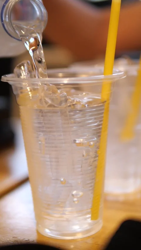 Close-up of pouring fresh drinking water from a bottle into a clear plastic cup Stock Footage 333853155