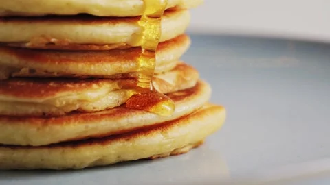 Close up pouring honey over stack of pancakes. Concept of sweet brunch. Stock Footage 319999229