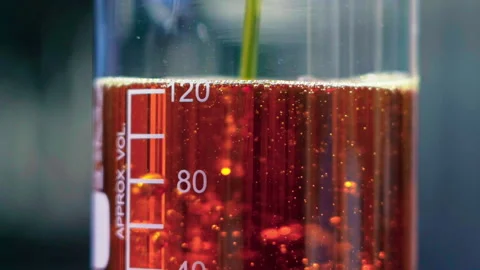 Close up pouring orange emulsion to beaker bokeh background 50fps Stock Footage 156063420