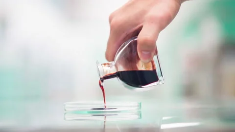 Close up pouring red brown liquid from glass bottle to flat glass container Stock-Footage 156240900