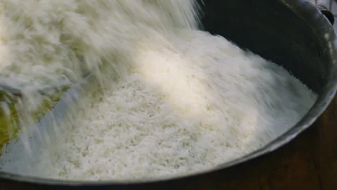 Close-up pouring rice into large kazan for Uzbek plov with sliced carrots Stock Footage 332863826