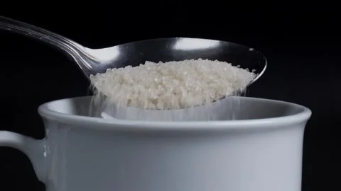Close up of pouring sugar with spoon into white mug isolated black background 库存影片 281639178