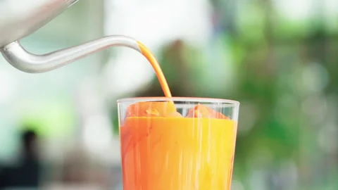Close up pouring thai tea from pot to glass with orange ice inside in white Stock Footage 156249028