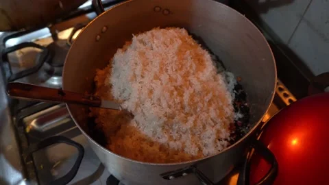Close up pouring uncooked rice into a kitchen pot with an arabic seasoning Stock Footage 145999195