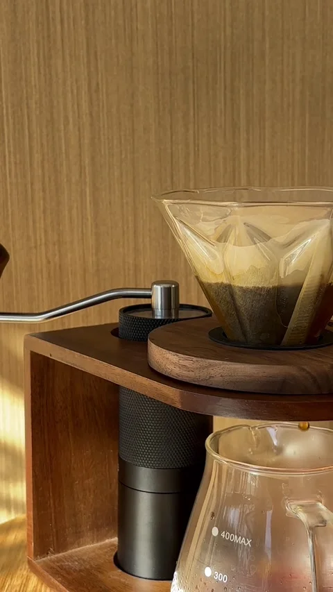 Close-up of pouring water from black kettle in v60 paper filter with fresh grind Vidéo 346688599