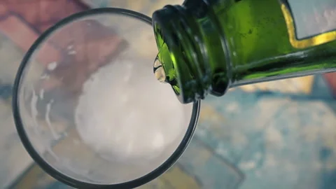 Close-up POV of Cold Beer Pouring from a Green Bottle into a Glass with Foam Stock Footage 335787956