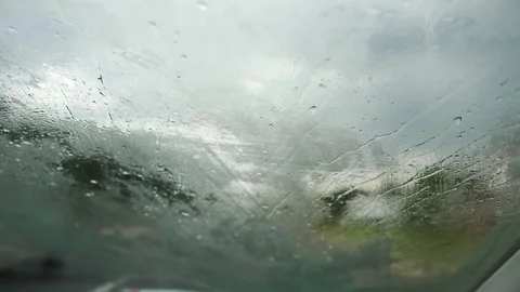 Close-up POV from inside a car onto raindrops on the windshield. Stock Footage 277114313