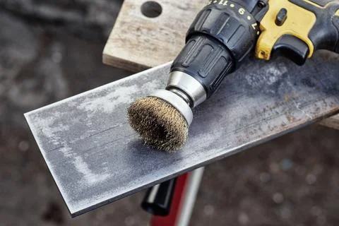Close up of power drill with wire brush cleaning metal surface. Metalworkin.. Stock Photos