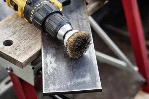 Close up of power drill with wire brush cleaning metal surface. Metalworkin.. Stock Photos