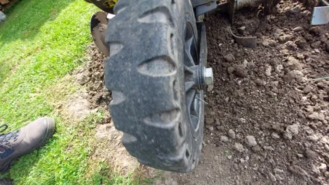Close-up of a power tiller wheel moving through tilled ground Stock Footage 334850858