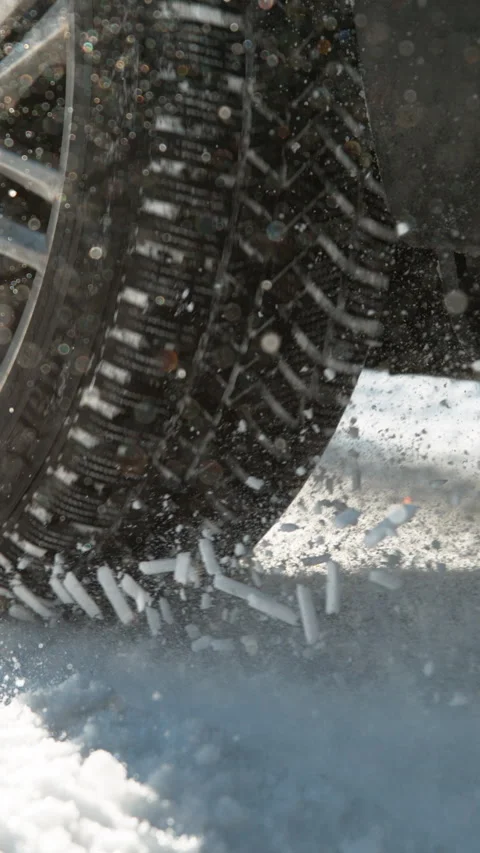 CLOSE UP: Powerful vehicle struggling to gain traction spews up pieces of snow. Video stock 315801170