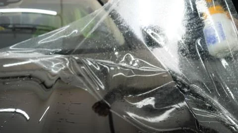 Close up to PPF installation process on a front headlight and hood. Stock Photos