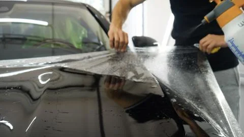 Close up to PPF installation process on a front headlight and hood. Stock Photos
