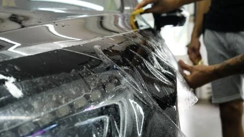 Close up to PPF installation process on a front headlight and hood. Stock-Fotos