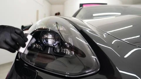 Close up to PPF installation process on a front headlight and hood. Stock-Fotos