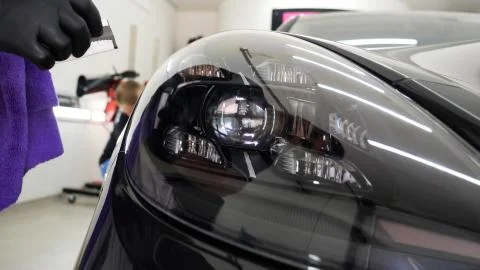 Close up to PPF installation process on a front headlight and hood. Stock-Fotos