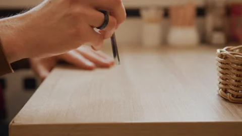 Close up precision cutting action person hand holding scissors above smooth wood Stock Footage 344866678