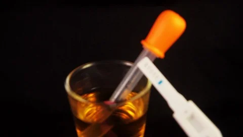 Close up of pregnancy test with the glass with urine on the side Stock Footage