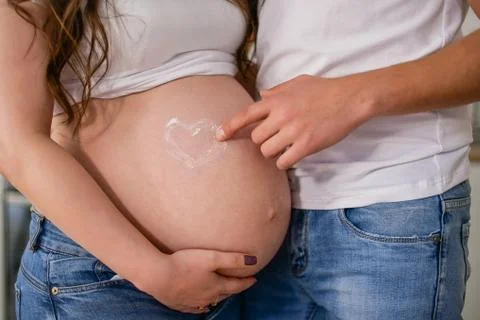  close up of pregnant belly with heart Stock Photos